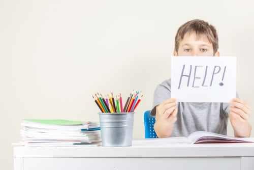 ילד עם שלט הקורא לעזרה עקב התמודדות עם לקויות וקשיי למידה