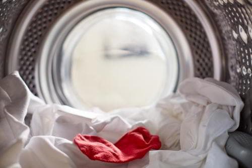גרב אדומה על בגדים לבנים במכונת כביסה